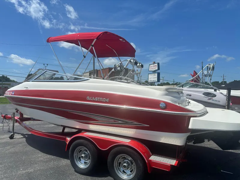 Slide: The Image of 2008 Glastron 205 GX boat with red and white design on a trailer under blue sky. - 2