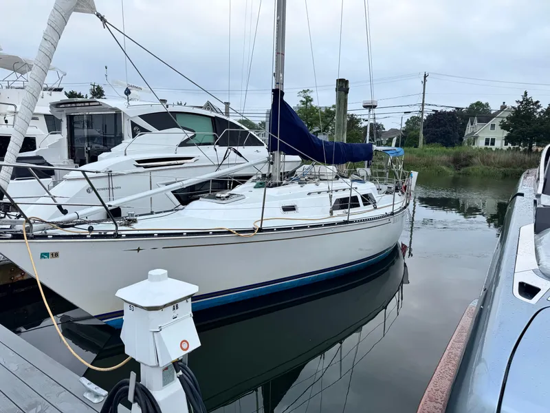 Slide: The Image of 1981 C&C 37 sailboat docked at marina, surrounded by other boats, calm water reflection. - 2