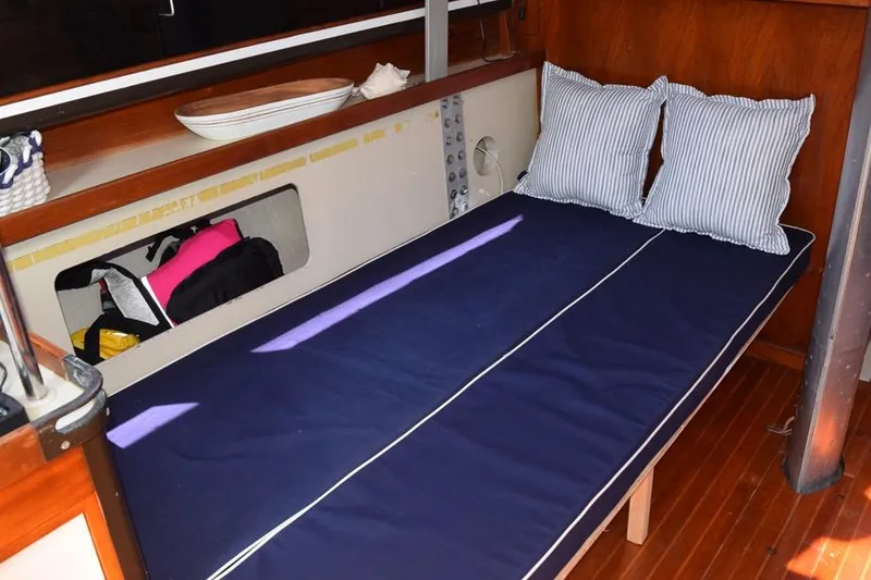 Slide: The Image of Interior of 1981 C&C 37 sailboat with blue cushioned berth and striped pillows. - 24