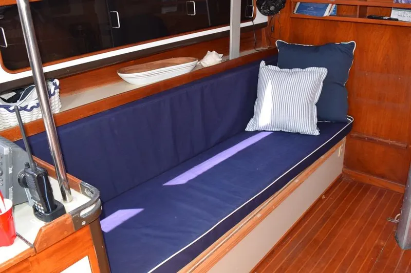 Slide: The Image of Interior of 1981 C&C 37 sailboat with blue cushioned seating and striped pillows. - 25