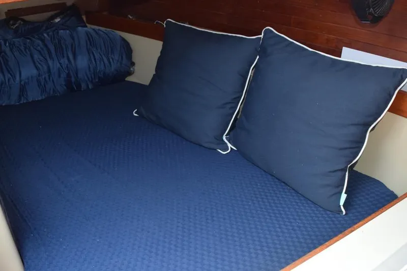 Slide: The Image of Cozy cabin bed with blue bedding and pillows on a 1981 C&C 37 sailboat. - 48