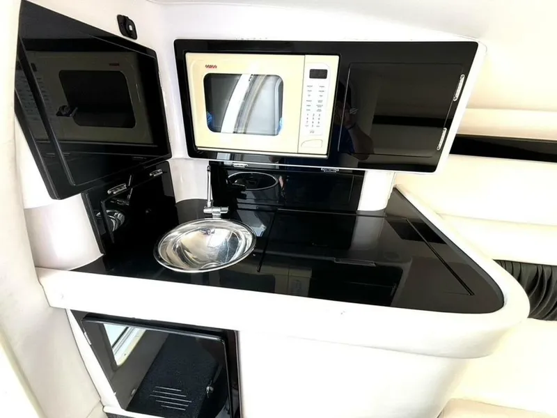 Slide: The Image of 2005 Donzi 33ZX boat interior with kitchenette, featuring a microwave, sink, and storage cabinets. - 35