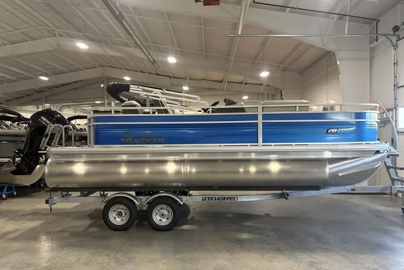 The Image of 2026 Sun Tracker Fishin' Barge 20 DLX pontoon boat in a showroom on a trailer. - 2