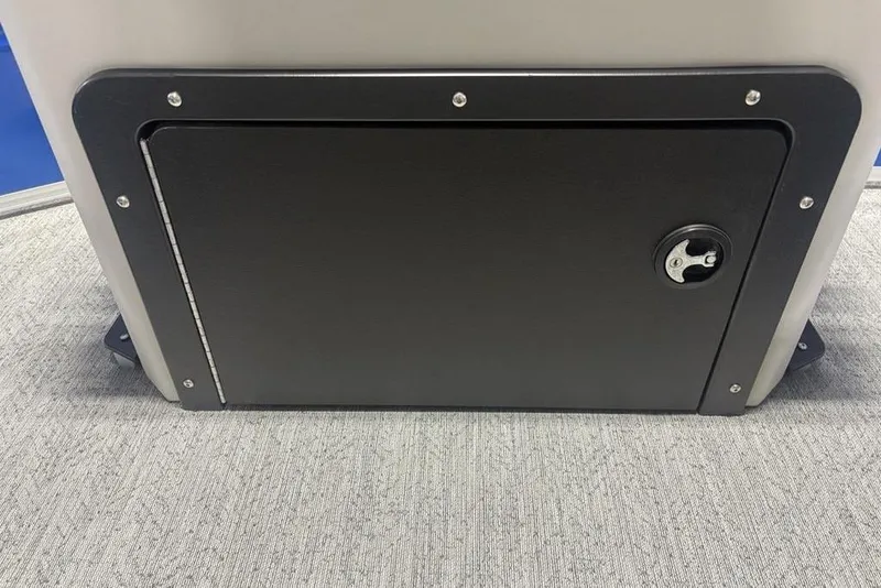 Slide: The Image of 2026 Sun Tracker Fishin' Barge 20 DLX storage compartment with secure latch on carpeted floor. - 29