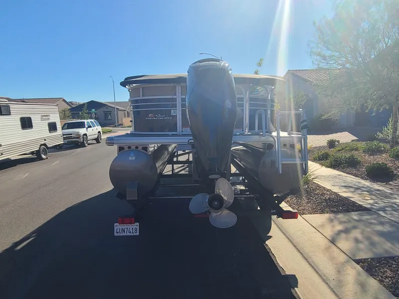 Slide: The Image of 2022 Sun Tracker Party Barge 20 DLX pontoon boat on trailer, parked in residential area. - 3