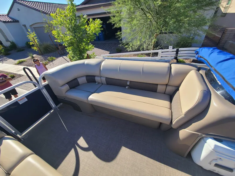 Slide: The Image of 2022 Sun Tracker Party Barge 20 DLX with beige seating, parked in a residential area. - 8