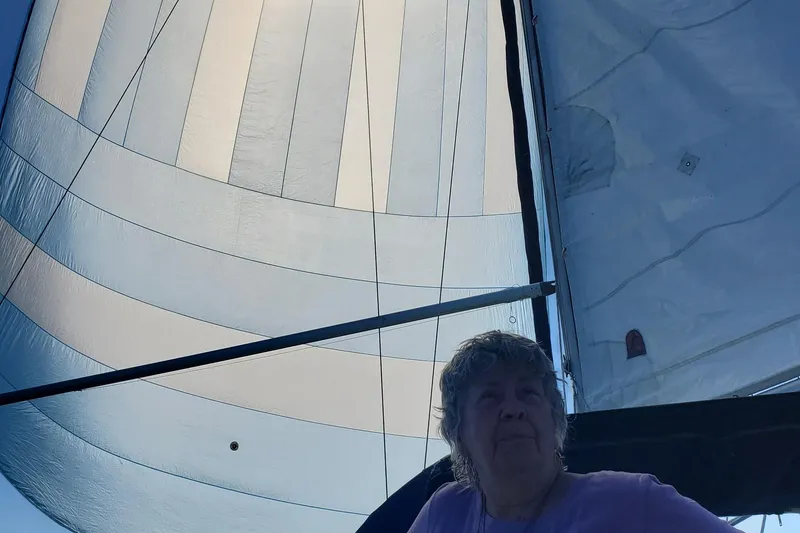 Slide: The Image of Elderly person sailing on a 1982 C&C 34 yacht with large sails overhead. - 10