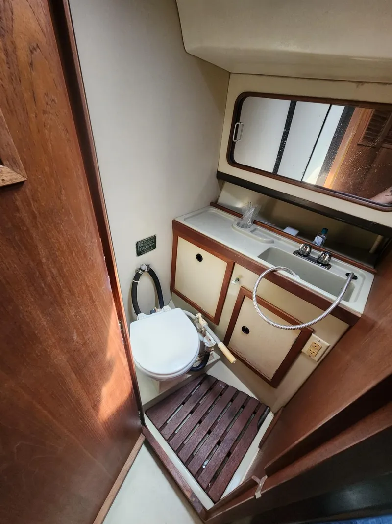 Slide: The Image of Compact 1982 C&C 34 yacht bathroom with toilet, sink, and wooden floor. - 19
