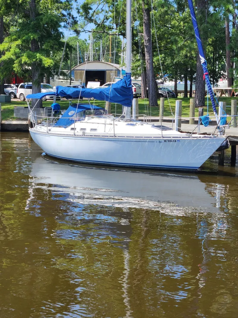 Slide: The Image of 1982 C&C 34 sailboat docked by a tree-lined marina. - 2