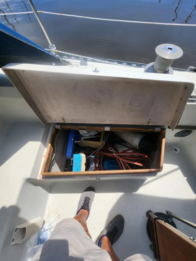 Slide: The Image of Open storage compartment on 1982 C&C 34 sailboat deck, containing various tools and equipment. - 28