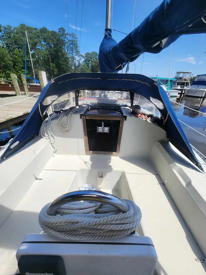 Slide: The Image of 1982 C&C 34 sailboat cockpit with blue canopy and coiled rope, docked at marina. - 6
