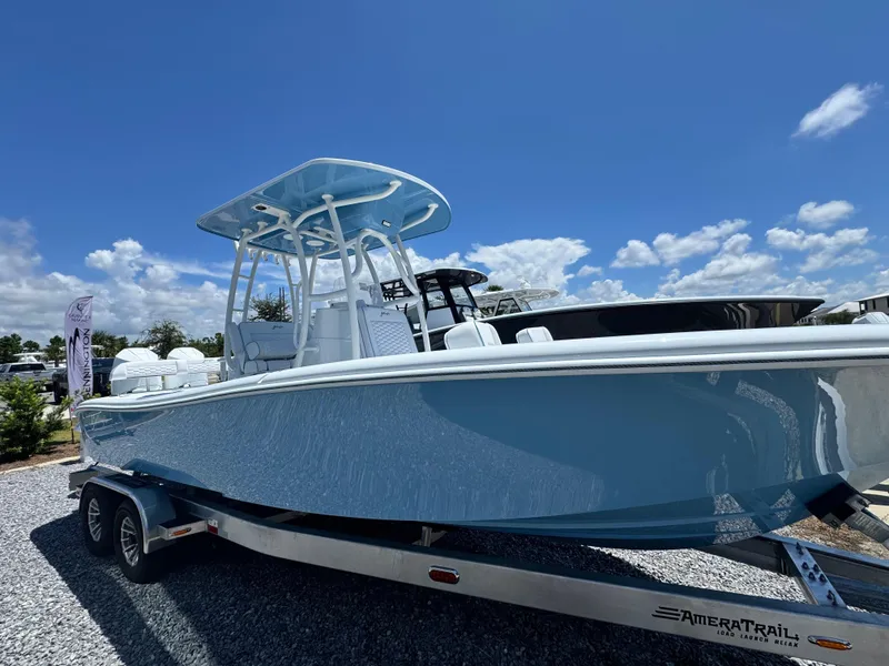 The Image of 2026 Yellowfin 26 Hybrid boat on trailer outside large warehouse. - 1