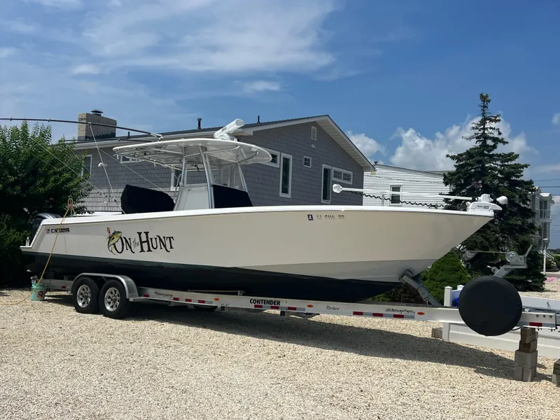 Slide: The Image of 2022 Contender 32 ST boat on trailer, parked near residential area under clear sky. - 1