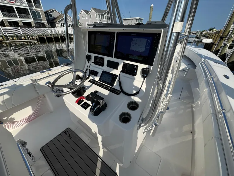 Slide: The Image of 2022 Contender 32 ST boat cockpit with modern controls and navigation systems, docked by waterfront homes. - 10