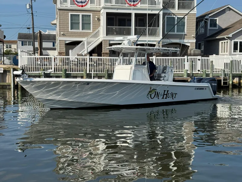 Slide: The Image of 2022 Contender 32 ST boat docked near waterfront homes, reflecting on calm water. - 2
