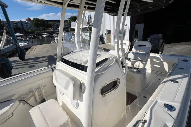 Slide: The Image of 2015 Boston Whaler 220 Outrage boat interior with seating and console, docked at marina. - 11