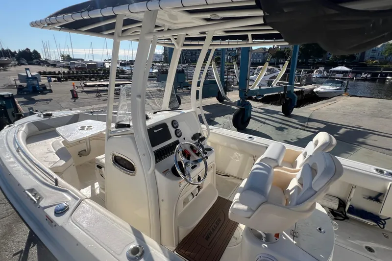 Slide: The Image of 2015 Boston Whaler 220 Outrage boat interior at marina, featuring helm and seating. - 12
