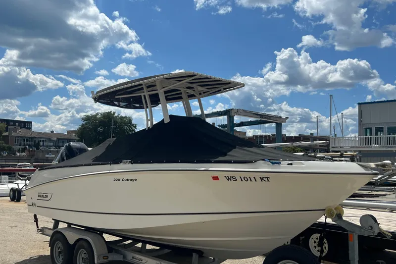 Slide: The Image of 2015 Boston Whaler 220 Outrage boat on trailer under blue sky. - 23