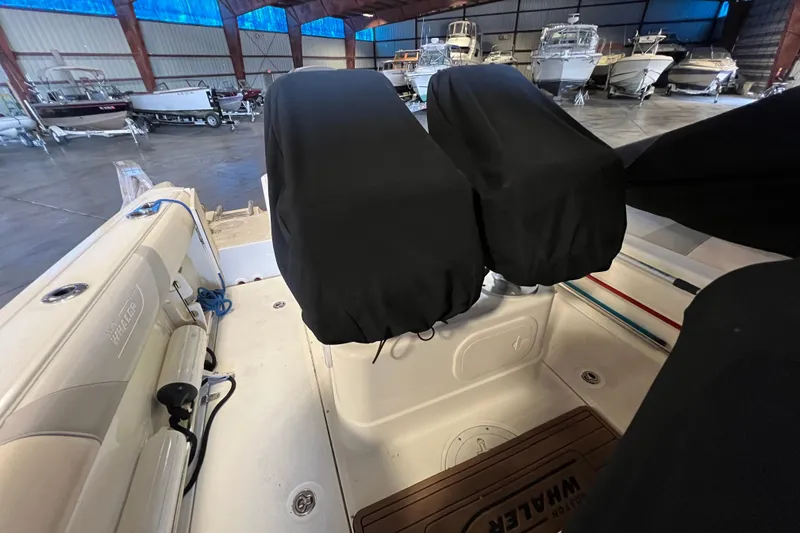 Slide: The Image of 2015 Boston Whaler 220 Outrage interior with covered seats in a boat storage facility. - 25