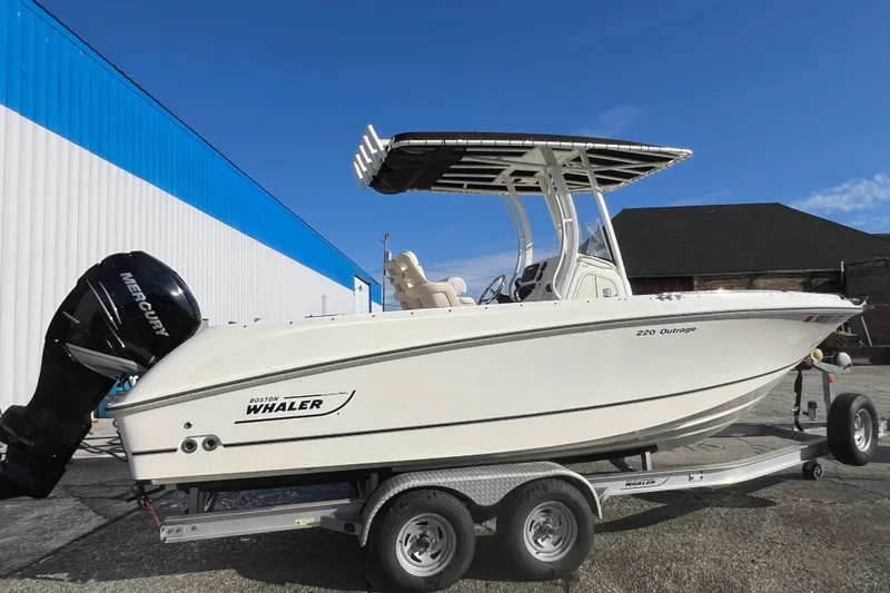Slide: The Image of 2015 Boston Whaler 220 Outrage boat on trailer, featuring Mercury engine, parked outdoors. - 8