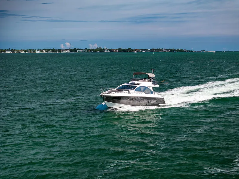 Slide: The Image of 2021 Azimut S6 yacht cruising on open water with distant shoreline. - 48