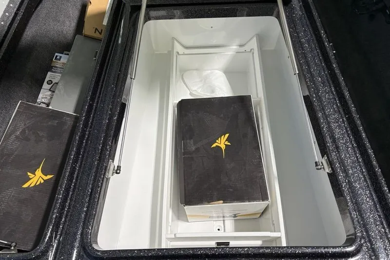 Slide: The Image of Open storage compartment in 2026 Phoenix 920 Elite X boat, featuring a black box with yellow logo. - 16