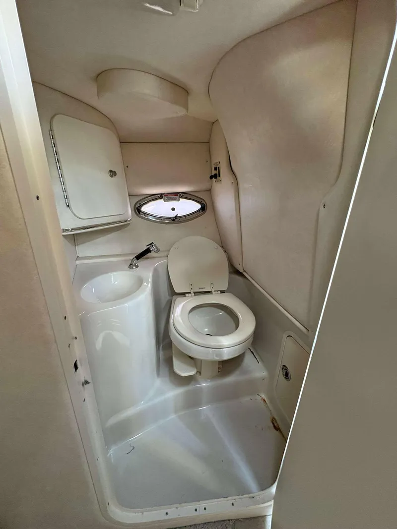 Slide: The Image of 2008 Sea Ray 290 SLX boat bathroom with toilet, sink, and porthole window. - 14