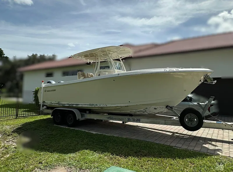 The Image of 2018 Sailfish 270 CC boat on trailer, surrounded by palm trees. - 0