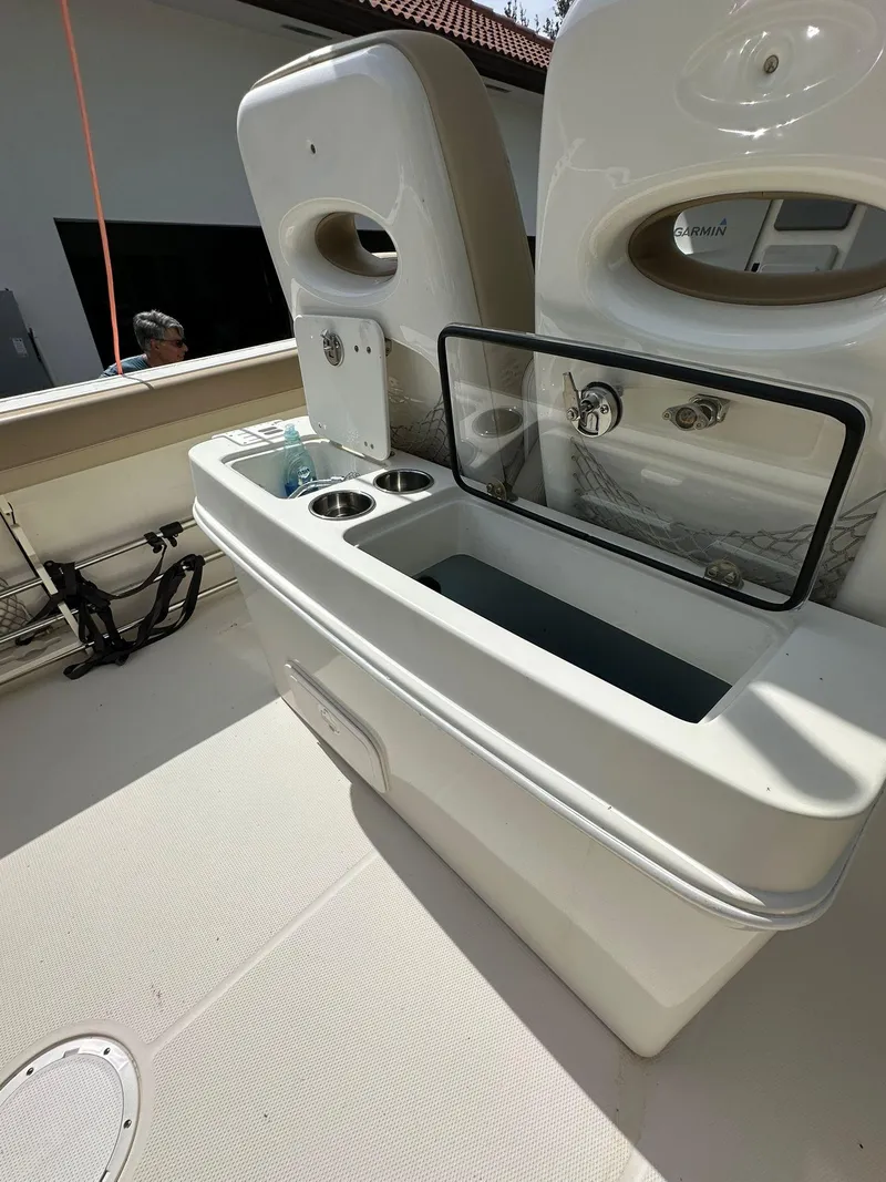 Slide: The Image of 2018 Sailfish 270 CC boat interior with seating and dual engines, parked near a house. - 10