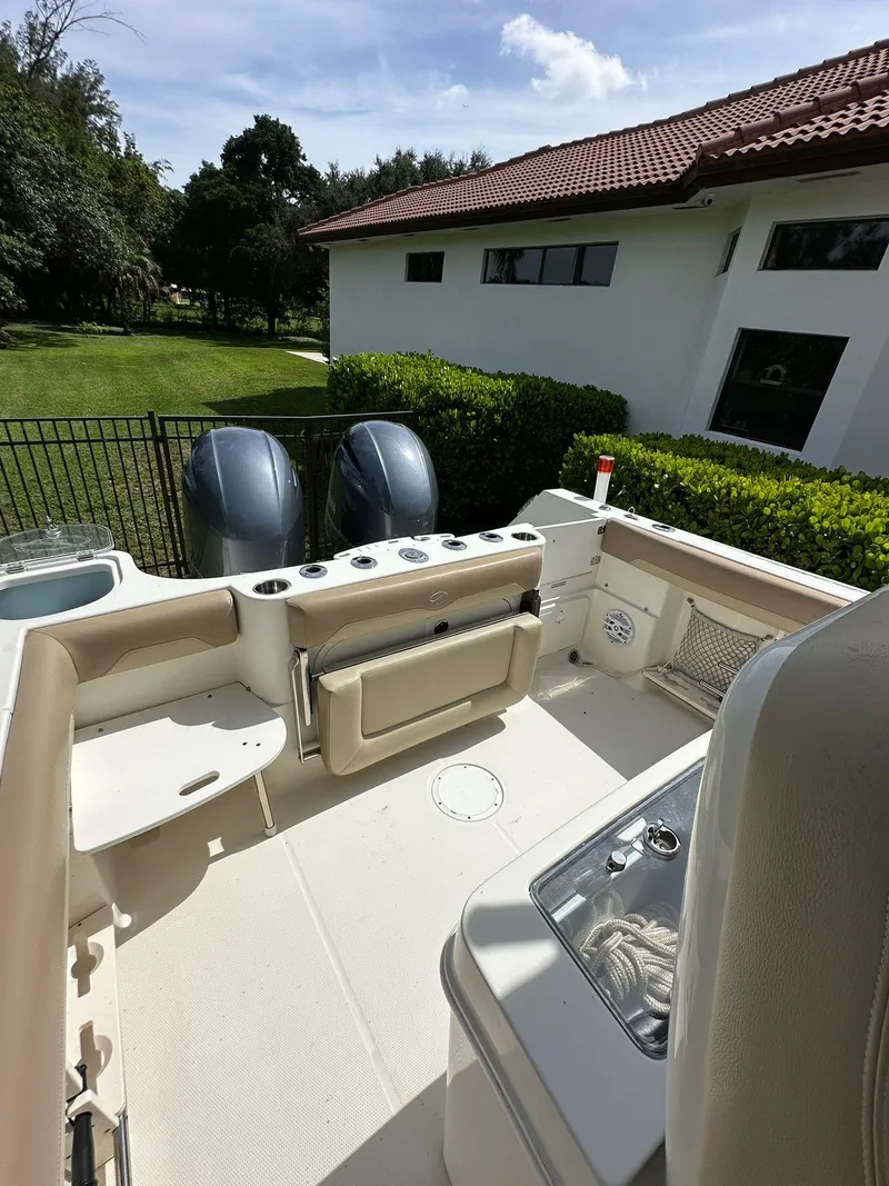 Slide: The Image of 2018 Sailfish 270 CC boat interior with seating and rod holders, surrounded by palm trees. - 12