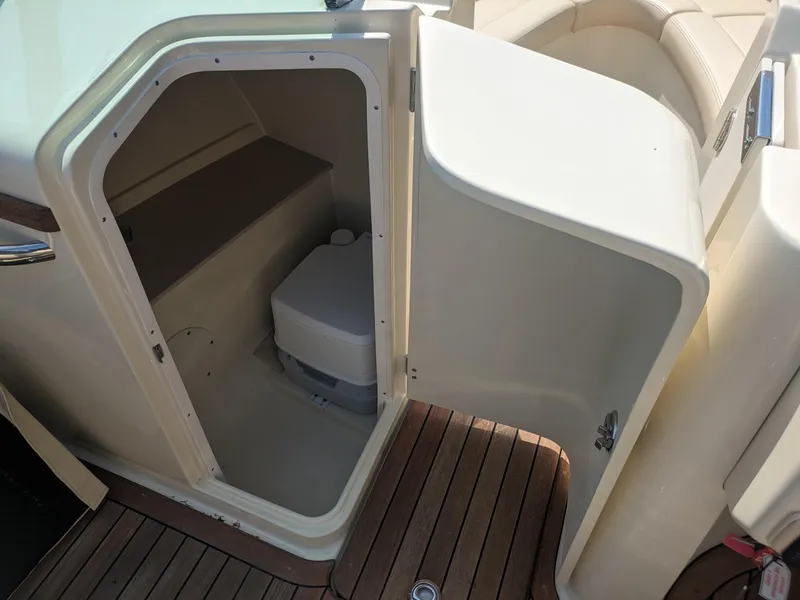Slide: The Image of 2018 Chris-Craft Launch 27 boat interior with open door revealing compact toilet. - 13