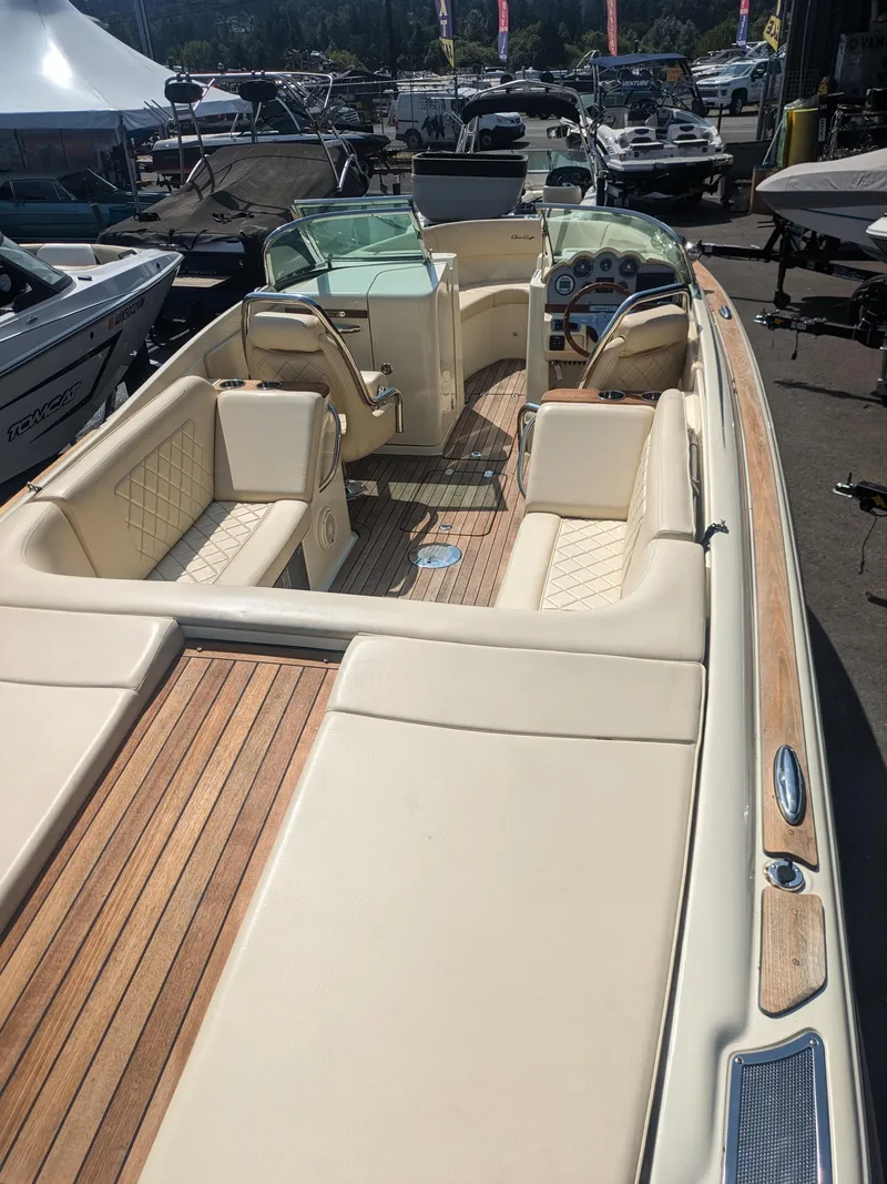 Slide: The Image of 2018 Chris-Craft Launch 27 boat with elegant seating and wooden deck, docked at a marina. - 16