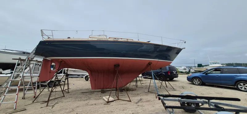 Slide: The Image of 1979 Bristol 35.5 sailboat on stands, with a red hull and blue top, in a boatyard. - 23