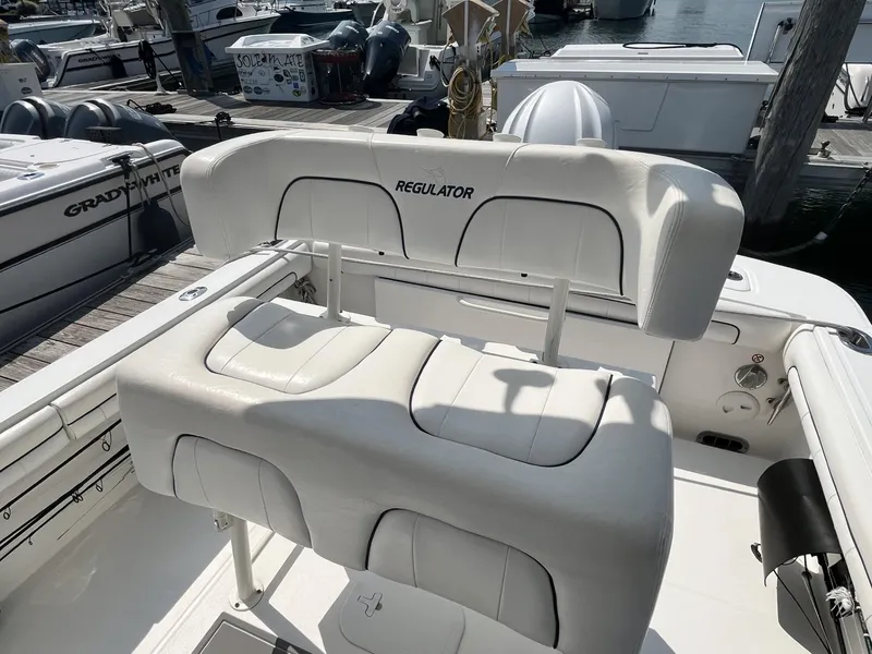 Slide: The Image of 2016 Regulator 23 boat with white cushioned seating at a marina. - 22