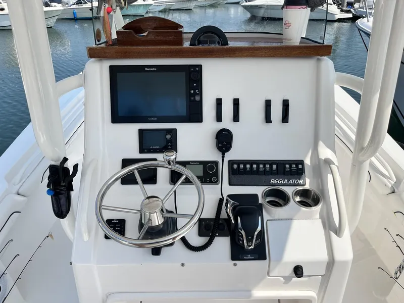 Slide: The Image of Control panel of a 2016 Regulator 23 boat with steering wheel and navigation equipment. - 24