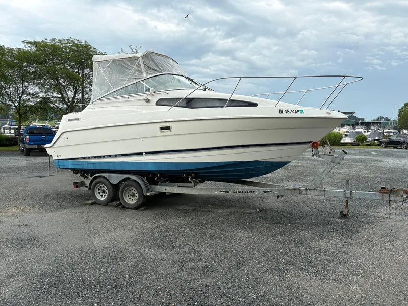 Slide: The Image of 1999 Bayliner 2355 Sunbridge boat on trailer, parked outdoors under cloudy sky. - 3