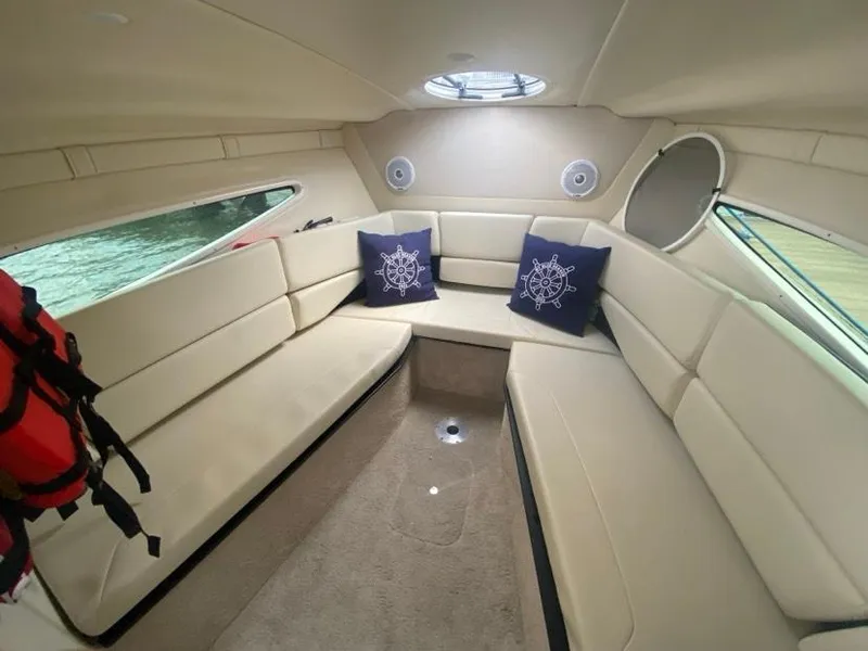 Slide: The Image of 2019 Regal 26 Express cabin interior with beige seating and nautical-themed pillows. - 13