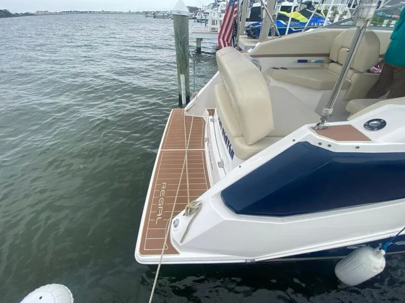 Slide: The Image of 2019 Regal 26 Express boat docked, featuring a spacious swim platform and comfortable seating. - 3