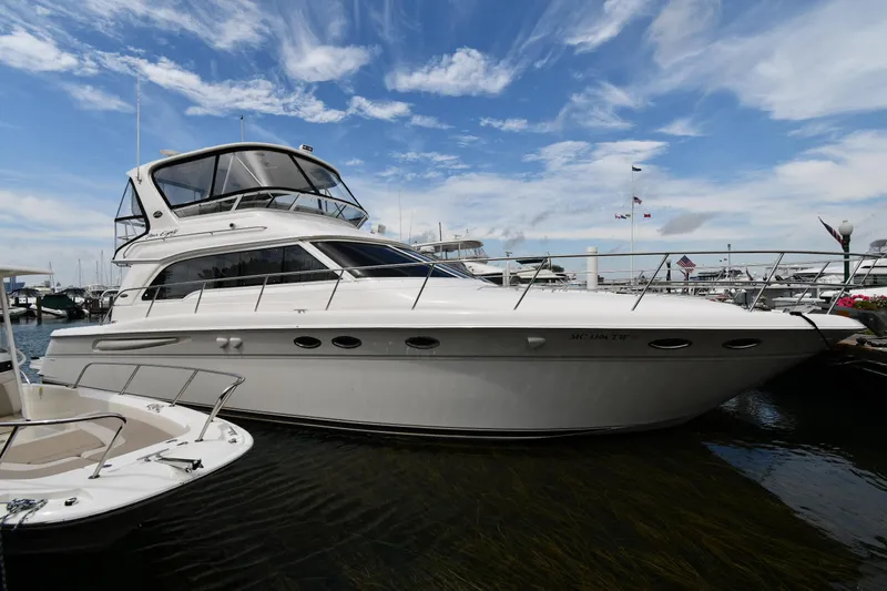 Slide: The Image of 2001 Sea Ray 480 Sedan Bridge yacht docked under a vibrant blue sky. - 0