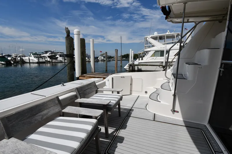 Slide: The Image of 2001 Sea Ray 480 Sedan Bridge yacht docked at marina, featuring spacious deck seating. - 12