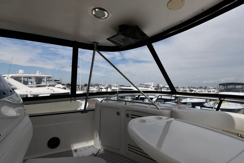 Slide: The Image of 2001 Sea Ray 480 Sedan Bridge interior with marina view, featuring seating and table. - 34