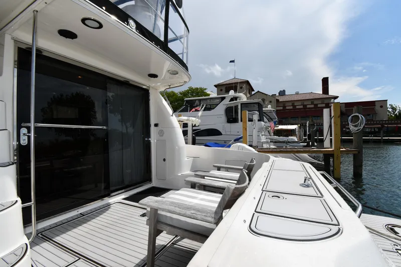 Slide: The Image of 2001 Sea Ray 480 Sedan Bridge yacht docked, featuring spacious deck and seating area. - 9