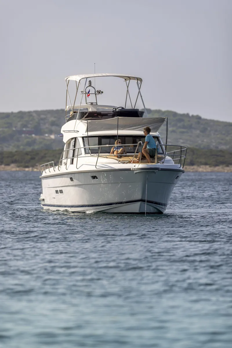 Slide: The Image of 2025 Nimbus 405 Flybridge yacht cruising on calm waters with passengers onboard. - 11