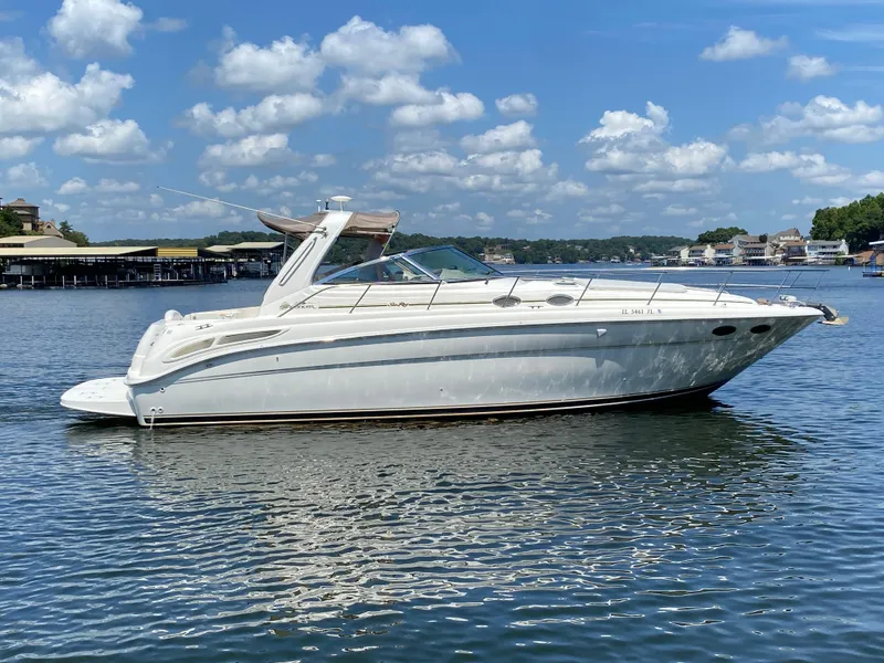 The Image of 1999 Sea Ray 380 Sundancer yacht on calm water under a blue sky with clouds. - 1