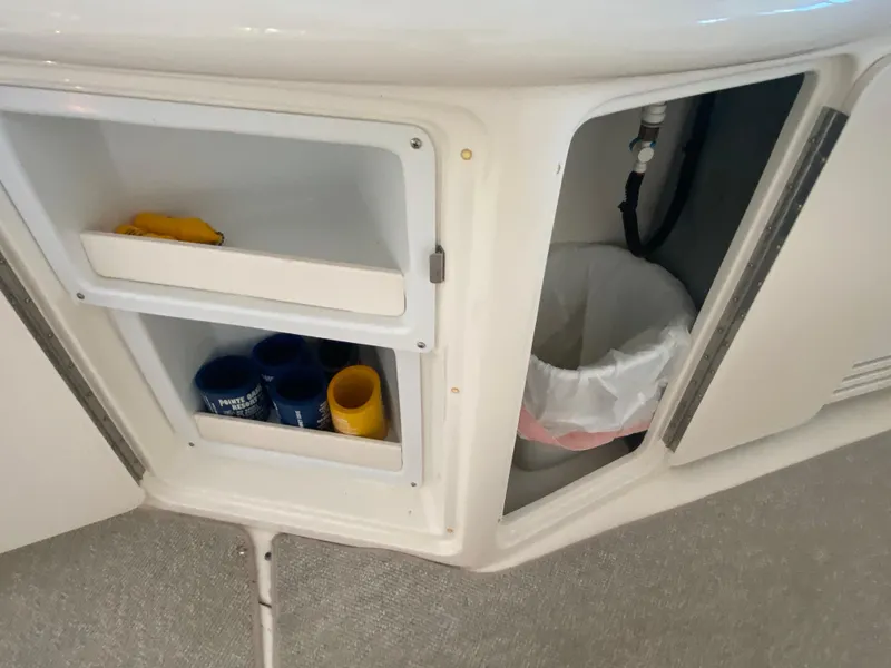 Slide: The Image of Open storage compartment on 1999 Sea Ray 380 Sundancer boat with cups and trash bin. - 10