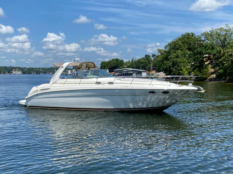 Slide: The Image of 1999 Sea Ray 380 Sundancer yacht cruising on a sunny lake with trees in the background. - 2
