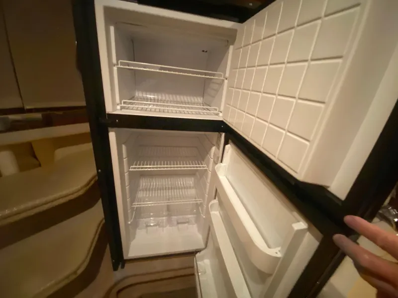 Slide: The Image of Open refrigerator inside a 1999 Sea Ray 380 Sundancer yacht, showing empty shelves. - 22