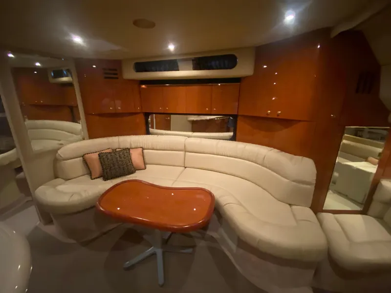 Slide: The Image of Luxurious interior of 1999 Sea Ray 380 Sundancer with plush seating and wooden table. - 23