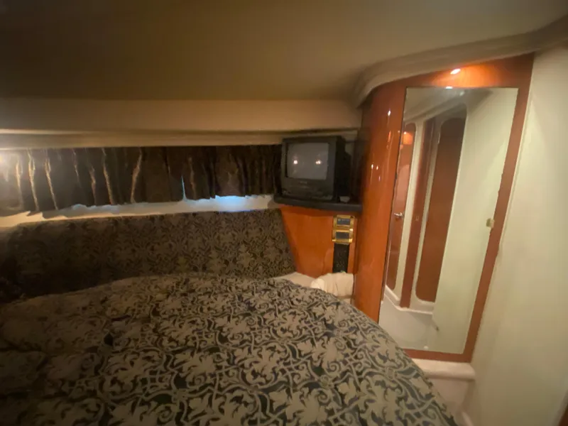 Slide: The Image of 1999 Sea Ray 380 Sundancer cabin interior with patterned bedding and vintage TV. - 27