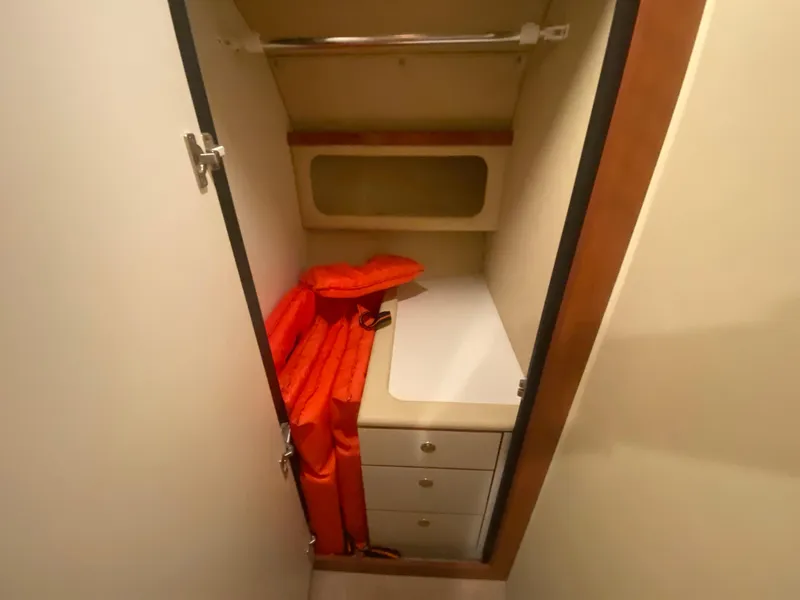Slide: The Image of 1999 Sea Ray 380 Sundancer cabin storage with orange life jackets and drawers. - 28